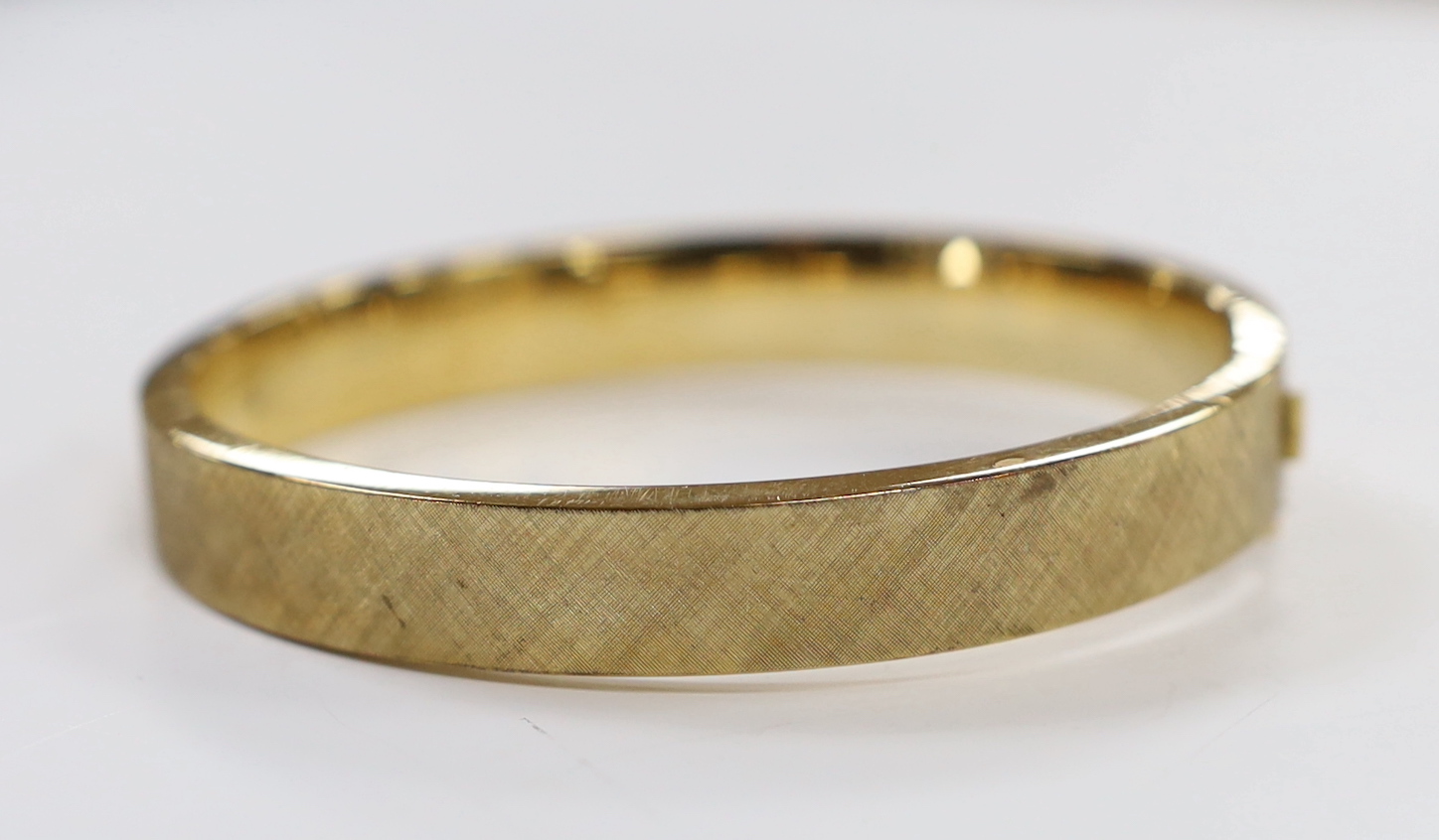 A brushed 9ct gold hinged bangle, interior diameter 63mm, 28.5 grams.